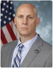 John Modlin, Acting Deputy Commissioner positioned in front of the American flag.