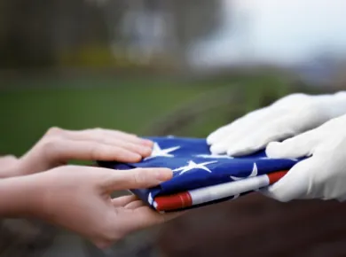 two sets of hands holding a folded American flag