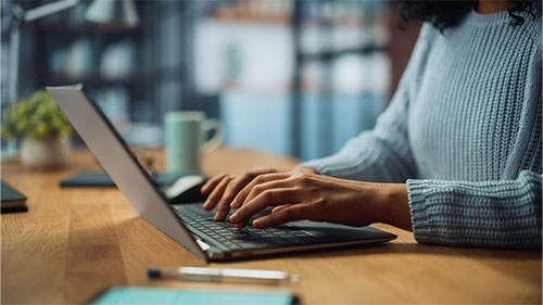 Close up of a woman's hand typing on a laptop