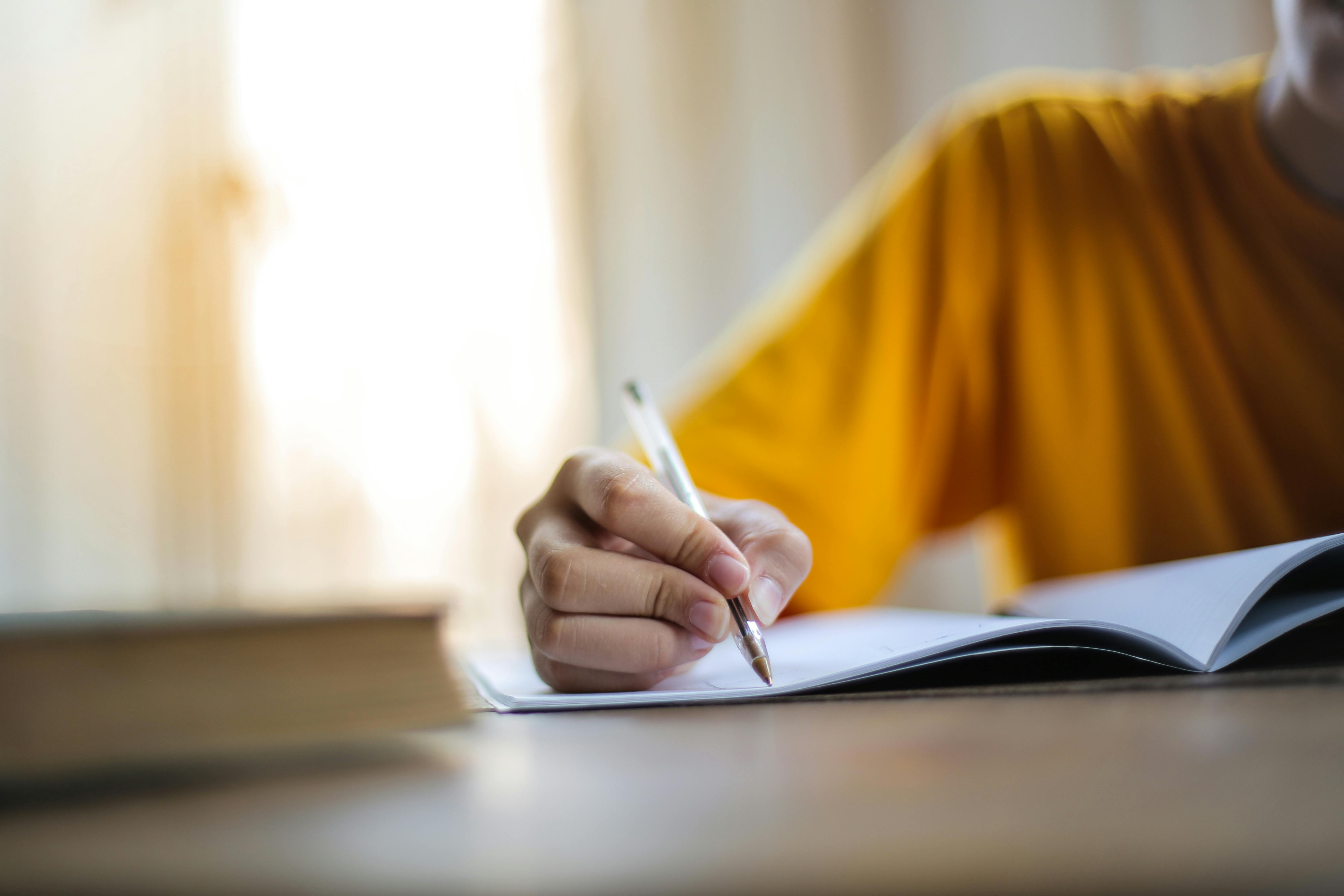 Individual using a pen to write on a piece of paper