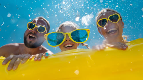 Family having fun on summer vacation. People jumping in swimming pool.