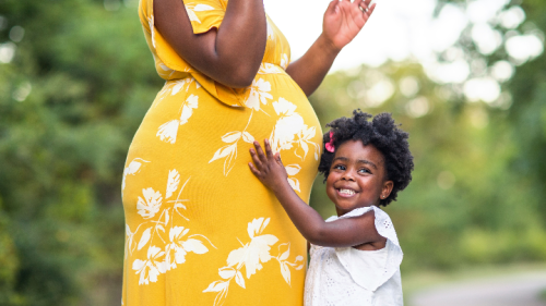 Little girl with hand on pregnant mom's belly