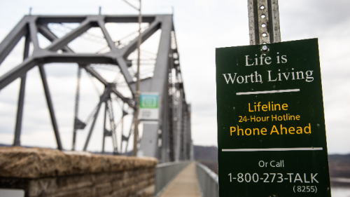 Suicide Prevention sign on a pole next to a bridge