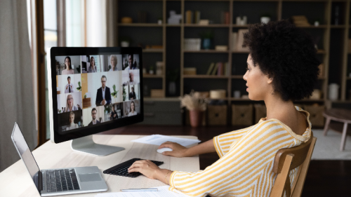 business woman holding video conference call conversation on computer with diverse colleagues, using different gadgets, sitting at table at workplace